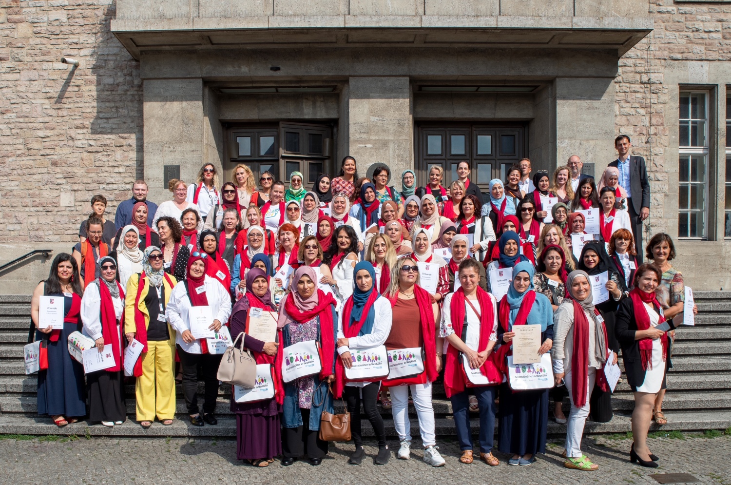 Gruppenbild: Über 70 Stadtteilmütter stehen vor dem Neuköllner Rathaus und freuen sich über ihre Zertifikate.