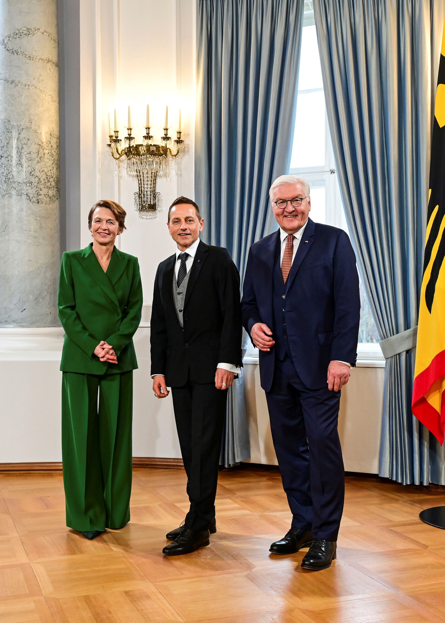 Elke Bündenbender, Thomas de Vachroi und Frank-Walter Steinmeier blicken lächelnd in die Kamera.