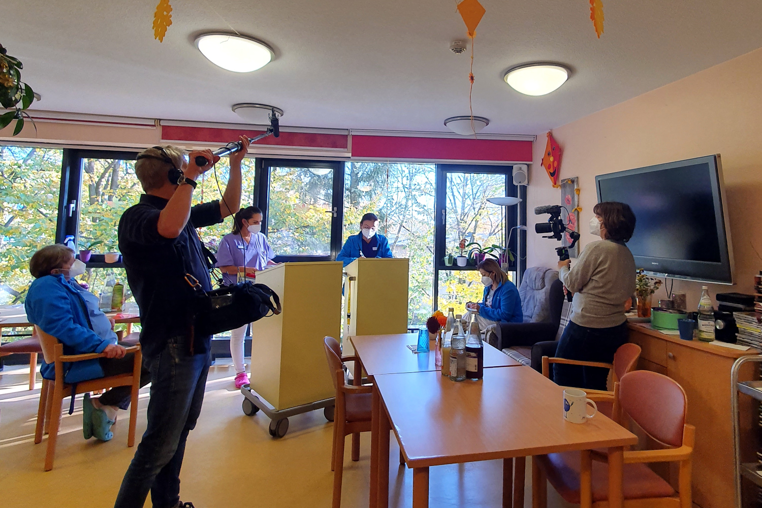 Ein Filmteam mit Tonangel und Kamera machen Aufnahmen von Pflegekräften im Pflegeheim.